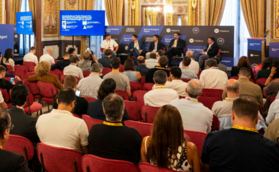 Un grupo de expectadores frente a un panel en un foro de criptomonedas en un auditorio de España.